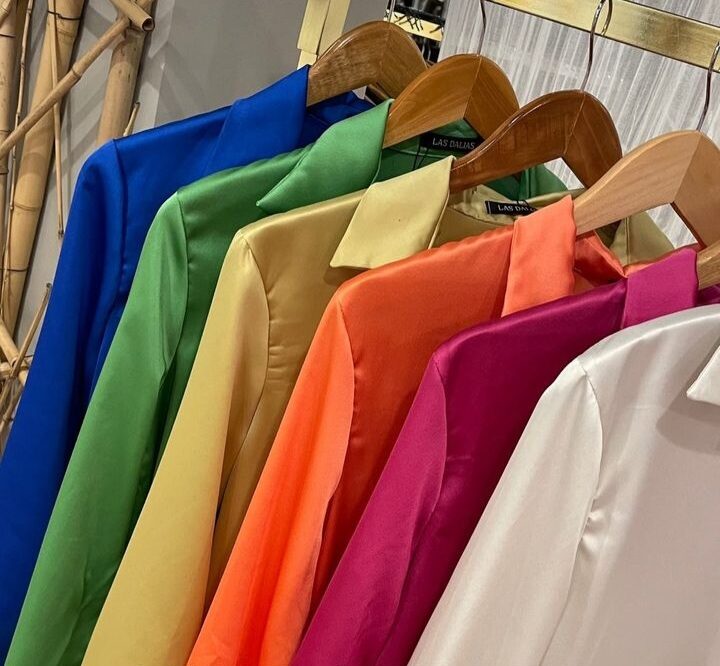 Prendas de trabajo de colores colgadas en percha en el taller de Córdoba