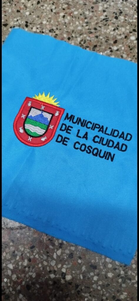 Escudo bordado a máquina de la Municipalidad de la Ciudad de Cosquín sobre paño celeste